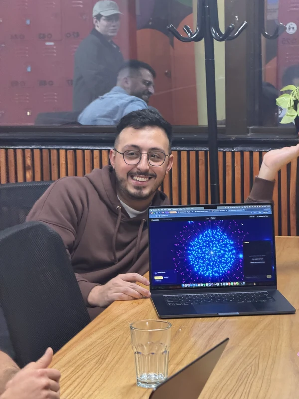 A teammate smiling beside a laptop showing a network data visualisation