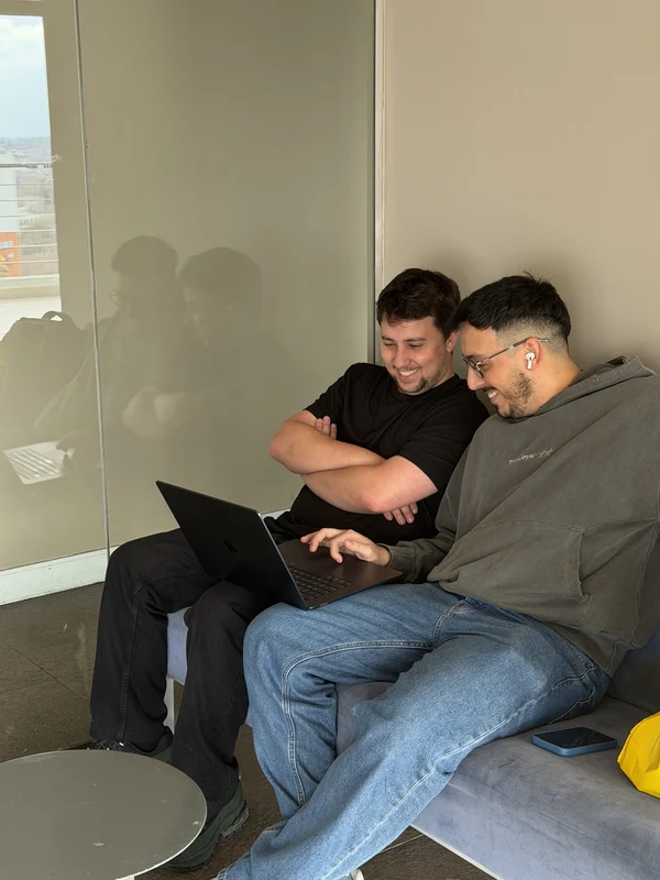 Two colleagues sharing a laptop on a low couch